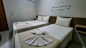 two beds in a room with a cross on them at Conforto Plaza Hotel in Capitão Leônidas Marques