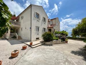 a large white house with potted plants in a courtyard at Vila Vera Seafront Apartments in Sumartin