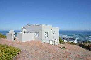 a white house on a hill near the ocean at Seaforever Apartment in Yzerfontein