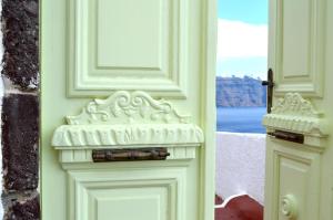 a green door with a stone archway with a window at Angel Cave Houses in Oia