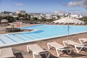 a swimming pool with lounge chairs and an umbrella at Caybeach Papagayos in Playa Blanca