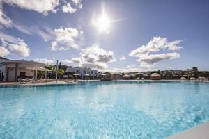 a large swimming pool with a blue sky and clouds at Caybeach Papagayos in Playa Blanca