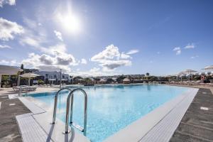 a large swimming pool with blue water and chairs at Caybeach Papagayos in Playa Blanca