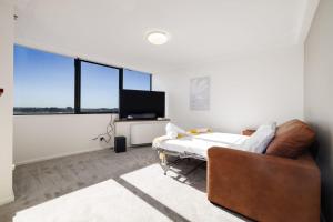 a living room with a couch and a tv and windows at CT&Mountain View on High level Riverfont Carpark in Brisbane