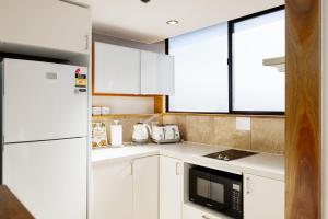 a kitchen with white cabinets and a white refrigerator at CT&Mountain View on High level Riverfont Carpark in Brisbane