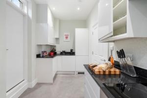 a kitchen with white cabinets and a black counter top at Chic 2 Bed Maisonette in Mayfair 32A in London