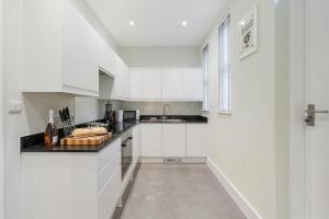 a white kitchen with white cabinets and a sink at Chic 2 Bed Maisonette in Mayfair 32A in London +43 photos