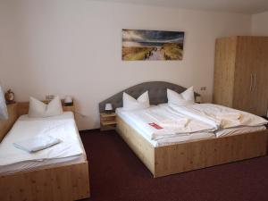 two beds in a hotel room with white sheets at Uschi's Gasthof in Neuendorf