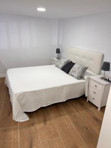 a bedroom with a large white bed and a wooden floor at AR Apartamentos Manzanares El Real in Manzanares el Real