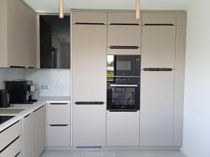 a white kitchen with white cabinets and appliances at Apartament Monika Dziwnówek Wrzosowo z jacuzzi in Wrzosowo