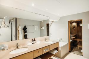 ein Badezimmer mit zwei Waschbecken und einem großen Spiegel in der Unterkunft Seehotel am Kaiserstrand in Lochau