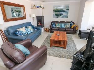 Una sala de estar con sofás, un televisor y una mesa. en Llain Gwynfor, en Haverfordwest