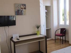 Habitación con escritorio, TV y silla. en Pub Vauban en Avallon