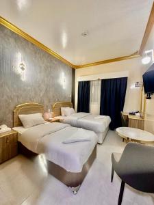 a hotel room with two beds and a desk at Galaxy Star Hotel in Dubai