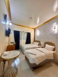 a hotel room with two beds and a table at Galaxy Star Hotel in Dubai
