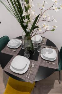 a black table with white plates and a vase of flowers at barneys design apartment in Taranto