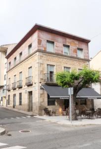 a building with tables and umbrellas in front of it at Christine Boutique Hotel in El Barraco