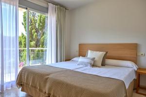 a bedroom with a large bed with a large window at Universal Aquamarin Beach Houses in Andratx +36 photos