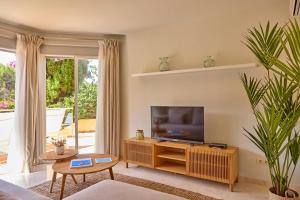 a living room with a flat screen tv on a wooden cabinet at Universal Aquamarin Beach Houses in Andratx