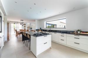 a kitchen with white cabinets and a dining room at Villa spacieuse et accueillante in La Roque-sur-Cèze