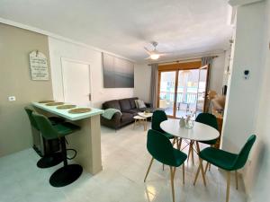 a living room with a table and green chairs at La Mata beach apartment Viñamar I, 200m from the beach in La Mata