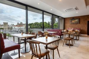 a restaurant with tables and chairs and large windows at Évora O Cante Hotel in Évora