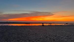 纳通市The Dreamcatcher Hostel Nathon SamuiSunset的日落时分坐在海滩上的人