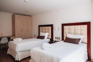 a bedroom with two beds and a desk at FRATELLI CORP APART HOTEL in La Paz