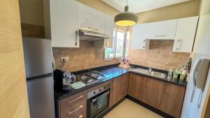 Una cocina con gabinetes blancos y un horno de estufa. en Dar Emna - Appartement de prestige sur golf, en Marrakech