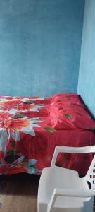 a bedroom with a red bed and a white chair at Paraíso a Beira Mar in Praia Da Caueira