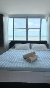 a bed with two towels on it with a large window at The Dreamcatcher or Samui sunset Hostel in Nathon