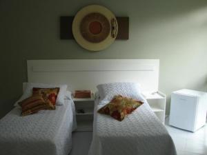 una camera da letto con due letti e un orologio a parete di Casa da Mila a Contagem
