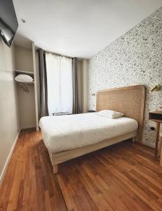 a bedroom with a bed with a wooden floor and a window at Le Florus in Montrouge