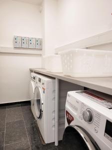 eine Waschküche mit Waschmaschine und Trockner unter der Theke in der Unterkunft Kostengünstige & charmante Ferienunterkunft ohne Küche und in Strandnähe - Ideal für Kurztrips oder 1-Nacht Aufenthalte in Scharbeutz
