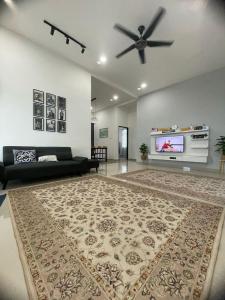 a living room with a black couch and a ceiling fan at Qayyum Homestay Pauh Lima,Bachok,Kelantan in Bachok