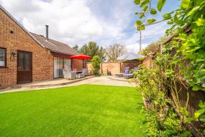 a garden with a lawn in front of a house at One Lazy Duck in Heacham
