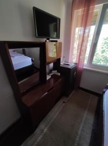 a bedroom with a tv and a dresser with a bed at Mercury Guest House in Veliko Tŭrnovo