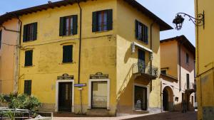 ein gelbes Gebäude mit schwarzen Fenstern an einer Straße in der Unterkunft Casa Maribel in Luino