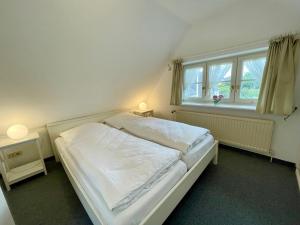 Una cama blanca en una habitación con ventana. en Amaris-Sylt, en Munkmarsch