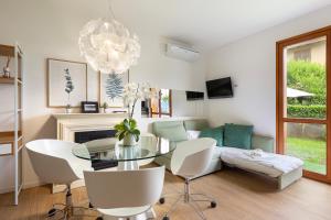 a living room with a glass table and white chairs at Appartamento Marina in Stresa