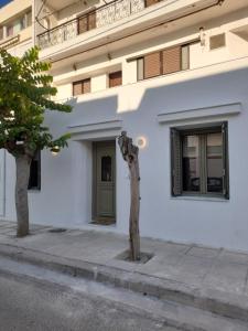 a white building with a green door and a tree at Kosmos Retreat in Kos