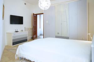 ein weißes Schlafzimmer mit einem Bett und einem Fernseher in der Unterkunft Casa Maribel in Luino