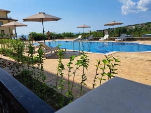 a swimming pool with chairs and umbrellas at Sun Holidays Byala in Byala