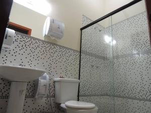 uma casa de banho com um WC e uma cabina de duche em vidro. em Itaipava Cama e Café em Itaipava