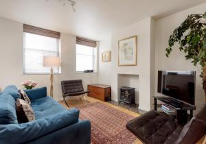 Una sala de estar con un sofá azul y un televisor. en Causewayside Apartment - The Edinburgh Address, en Edimburgo