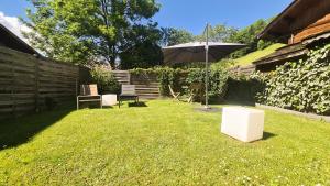 a yard with an umbrella and a chair and a table at Le Grenier 1821 - Mini chalet - Centre village - AravisTour in Saint-Jean-de-Sixt