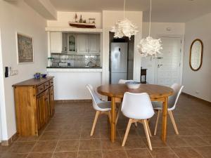 a kitchen with a wooden table and white chairs at Apartamento El Palmeral Aguadulce in Aguadulce