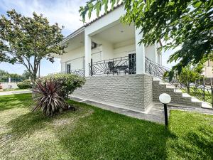 a white house with a porch and grass at The Serenity Villa #PROPERTLY in Nea Kallikrateia