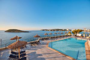 a resort with a swimming pool with umbrellas and the ocean at Hotel Florida Magaluf - Adults Only in Magaluf