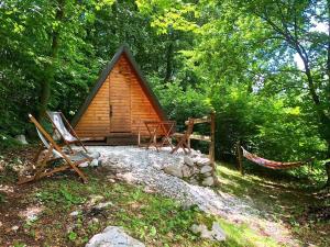 a cabin with chairs and a hammock in front of it at Glamping Krn in Kobarid